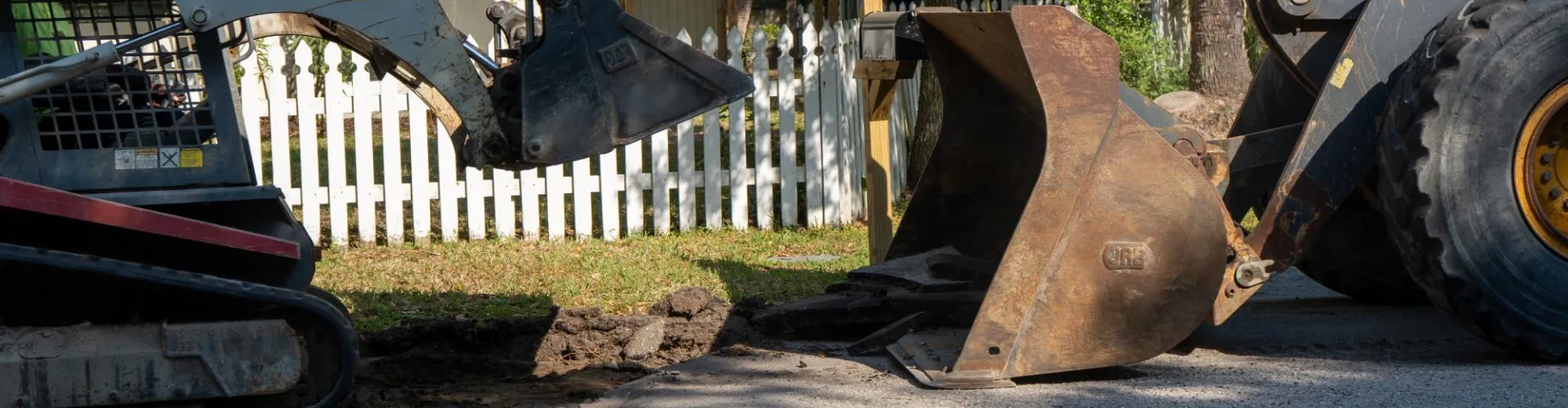 A digger digging up the existing asphalt sidewalk