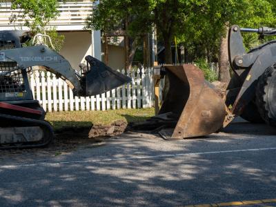 A digger digging up the existing asphalt sidewalk
